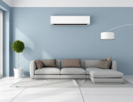 Blaues Wohnzimmer mit grauem Sofa und Klimaanlage an der Wand.