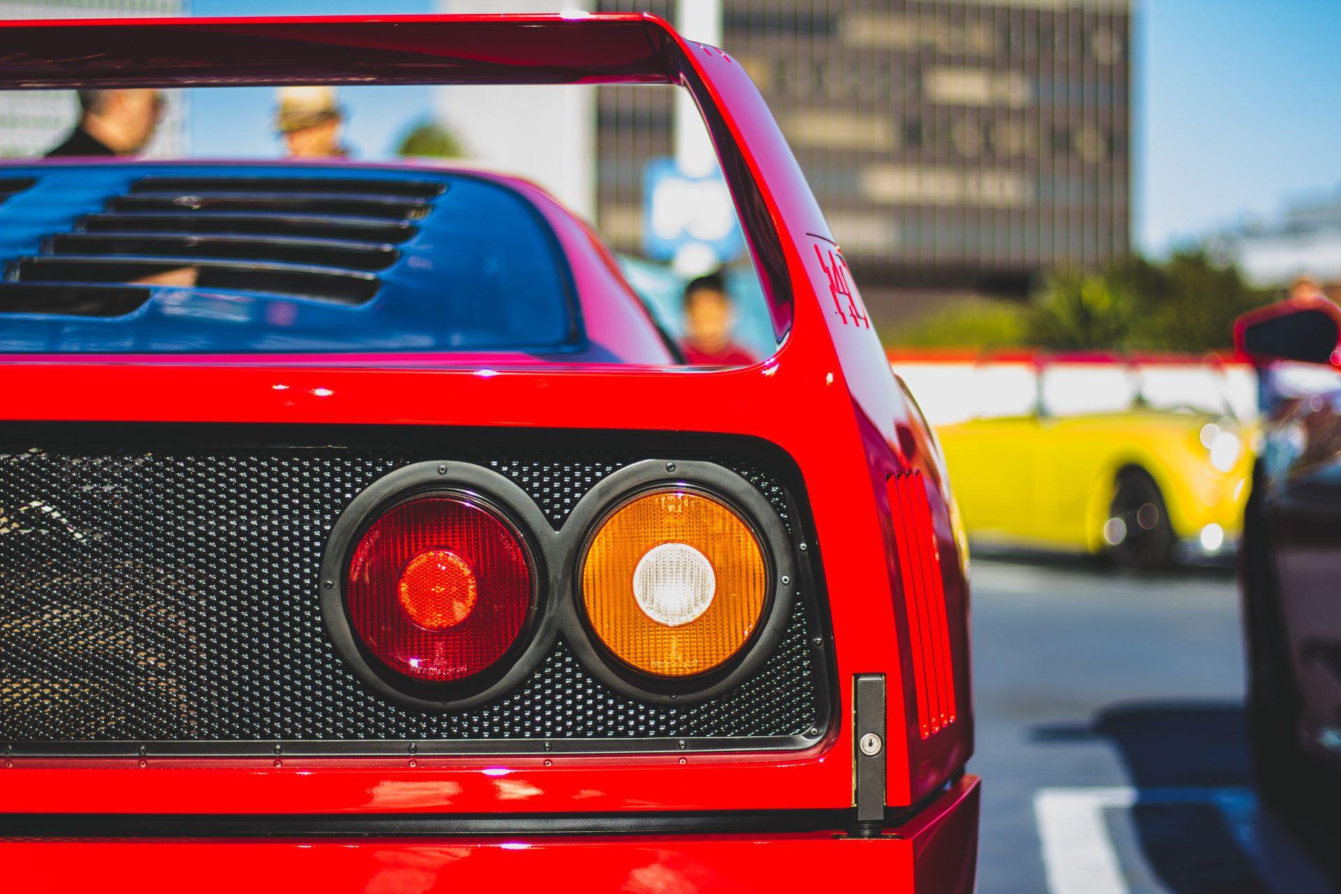 Rote Ferrari-Heckansicht mit ikonischen runden Rücklichtern auf einem Parkplatz, perfekte Wahl für Ferrari mieten.