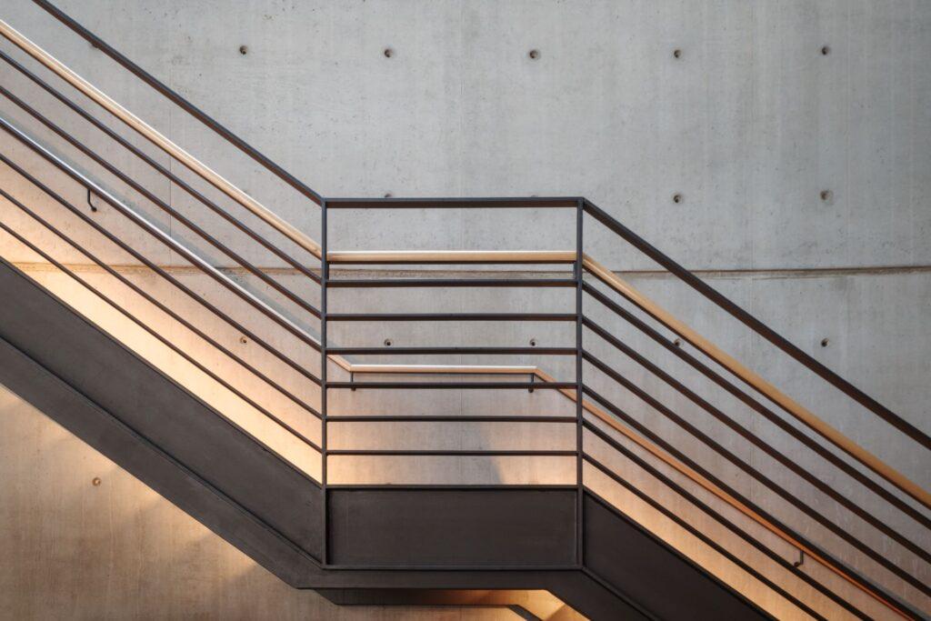 Industrielles Edelstahlgeländer mit Holzhandlauf an Betontreppe